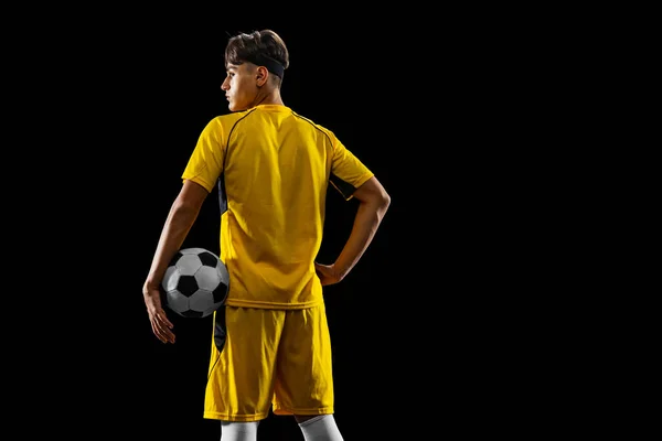 Portret młodego profesjonalnego piłkarza odizolowanego na czarnym tle. Widok z tyłu — Zdjęcie stockowe
