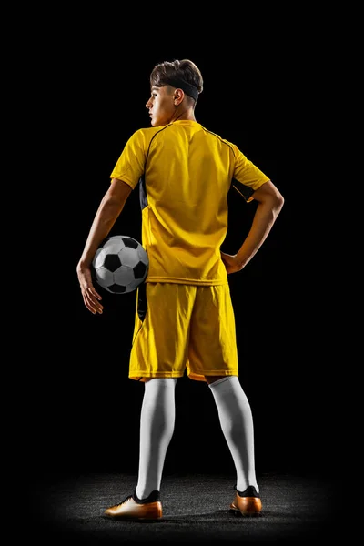 Ritratto a figura intera di giovane calciatore professionista isolato su sfondo nero. Vista posteriore — Foto Stock