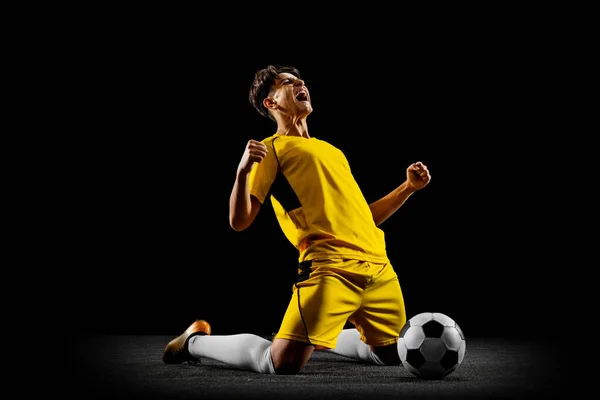 Ganzes horizontales Porträt eines jungen Mannes, männlicher Fußballspieler, der isoliert auf schwarzem Hintergrund trainiert. — Stockfoto