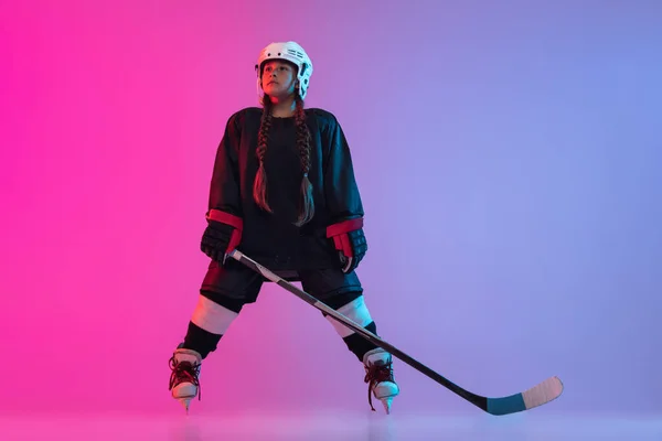 Sport motivation. Discipline. Image of little girl, professional hockey player, training isolated isolated over gradient pink purple background. Concept of active life, team game, energy, sport, ad.