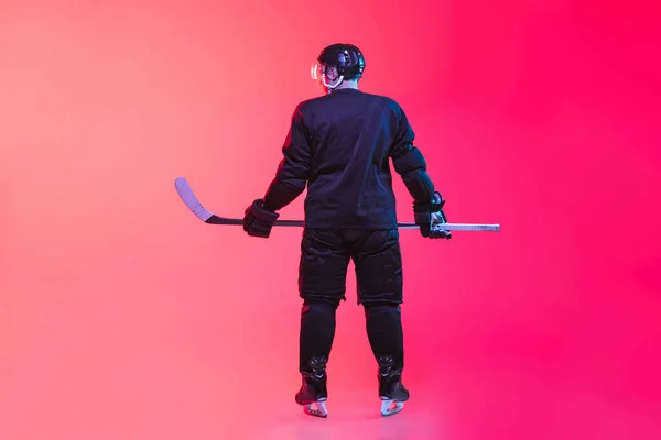 Vista posterior imagen completa de jugador de hockey profesional en uniforme aislado sobre fondo rosa degradado en neón — Foto de Stock