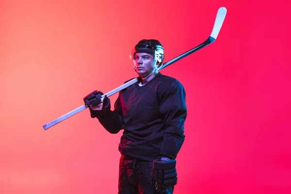 Oříznutý obraz profesionálního hokejisty v uniformě s hůlkou izolované přes gradient růžové pozadí v neonu. Boční pohled — Stock fotografie