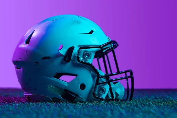 Studio side view shot of professional equipment - protective helmet - for american football game isolated over purple background in neon lights — 图库照片