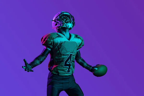Un jugador de fútbol americano profesional en unofrm especial aislado sobre fondo de estudio púrpura. Entrenamiento de campeonato — Foto de Stock