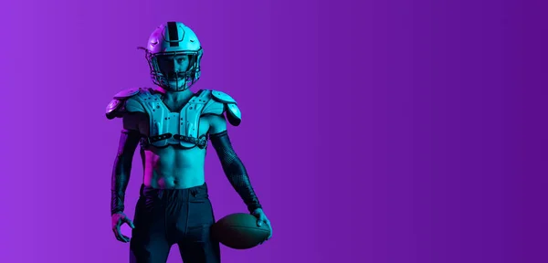 Zugeschnittene Weitwinkelbild des männlichen Sportlers, professionelle American Football-Spieler trägt Helm und Schulterpolster isoliert über lila Hintergrund — Stockfoto