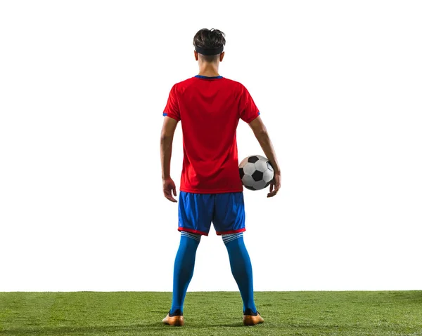 Volver ver retrato de joven jugador de fútbol caucásico i uniforme sosteniendo pelota aislado en el suelo de hierba fondo blanco —  Fotos de Stock