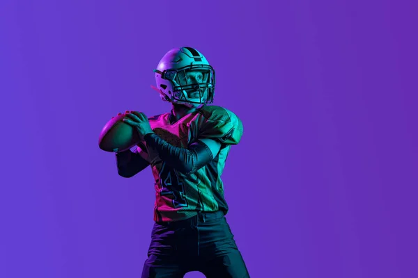 Un jugador de fútbol americano profesional en unofrm especial aislado sobre fondo de estudio púrpura. Entrenamiento de campeonato — Foto de Stock