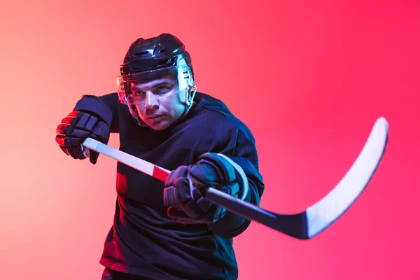 Un hombre, entrenamiento profesional jugador de hockey aislado sobre fondo rosa degradado en neón — Foto de Stock