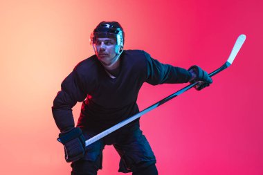 Profesyonel hokey oyuncusunun portresi neon ışıkta izole edilmiş.