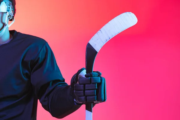 Details. Ausgeschnittenes Bild eines Eishockeyspielers in Uniform mit Hockeyschläger auf rosa Hintergrund — Stockfoto