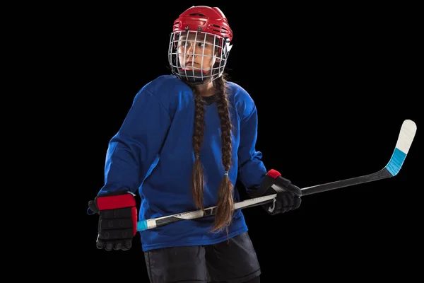 One young girl hockey player training isolated over black background