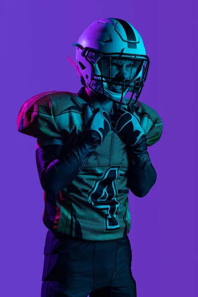Un jugador de fútbol americano profesional en unofrm especial aislado sobre fondo de estudio púrpura. Mirada expresiva — Foto de Stock