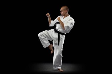 Siyah arka planda karate yapan genç sporcunun tam boy görüntüsü izole edildi