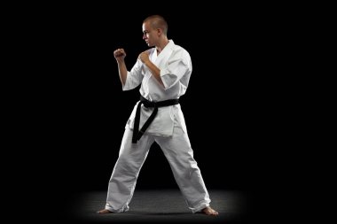 Siyah arka planda karate yapan genç sporcunun tam boy görüntüsü izole edildi