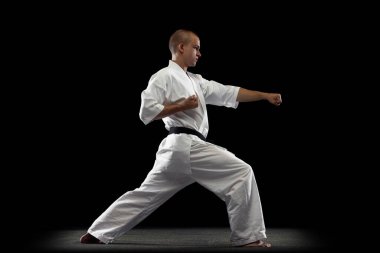 Siyah arka planda beyaz kimono giyen genç sporcu Karateka 'nın tam boy portresi.