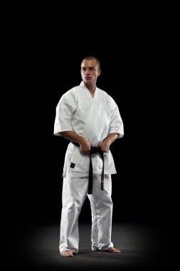 Siyah arka planda izole edilmiş beyaz kimonolu genç profesyonel karate sporcusunun tam boy portresi