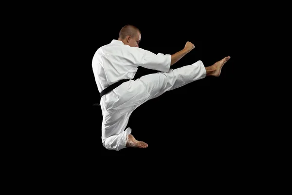Ett långt porträtt. En ung karate idrottsman utbildning isolerad över svart bakgrund. Sidovy — Stockfoto