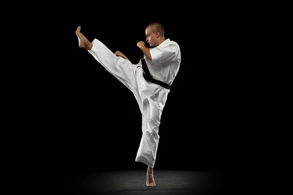 One young sportsman practising karate isolated over black background — Stock Photo, Image