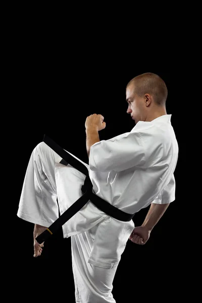 Retrato de cuerpo entero del joven deportista entrenando karate aislado sobre fondo negro — Foto de Stock