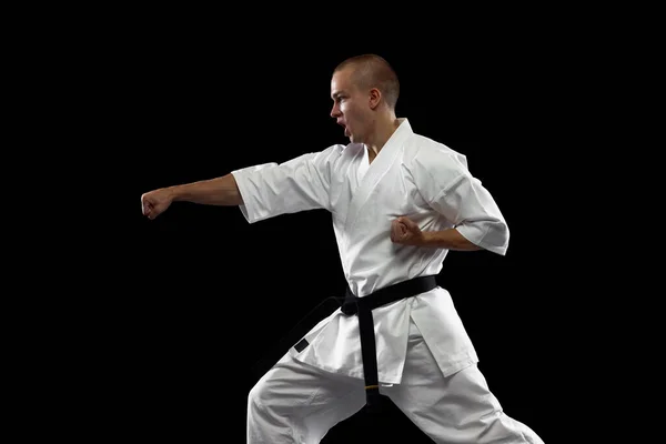 Ritratto a figura intera di giovane sportivo, karateka, con indosso kimono bianco isolato su sfondo nero — Foto Stock