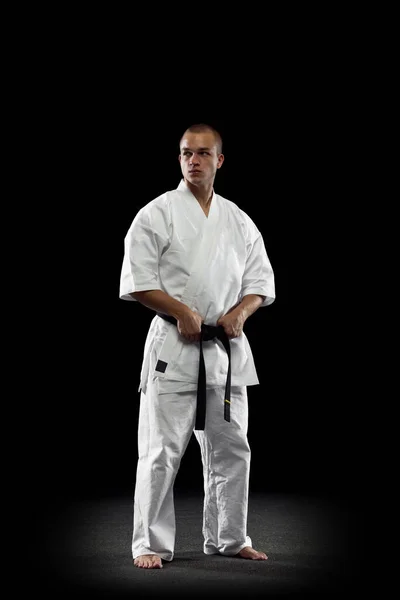 Full längd porträtt av ung professionell karate idrottsman i vit kimono isolerad över svart bakgrund — Stockfoto