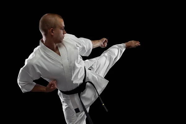 Beskurna porträtt av ung karate idrottsman utbildning isolerad över svart bakgrund — Stockfoto