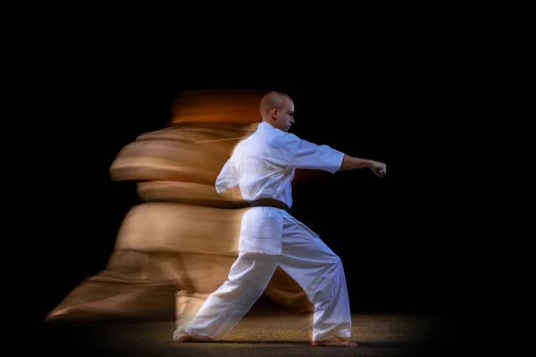 Retrato de cuerpo entero del joven deportista de karate usando kimono blanco aislado sobre fondo negro. Efecto de luz mixta —  Fotos de Stock