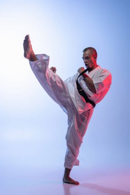 Kimono giymiş beyaz bir adamın portresi. Gradyan beyaz mavi arka planda dövüş sanatı eğitimi veriyor. Karate, judo, tekvando sporu.