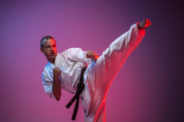 Kimono giymiş yakışıklı beyaz adamın gradyan pembe arka planda dövüş sanatı eğitimi alan portresi. Karate, judo, tekvando sporu