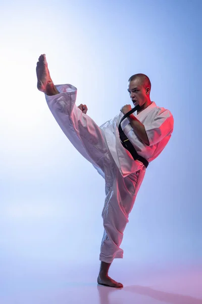 Portret białego mężczyzny w kimono trenującego sztukę walki na gradientowym białym niebieskim tle. Karate, judo, sport taekwondo. — Zdjęcie stockowe