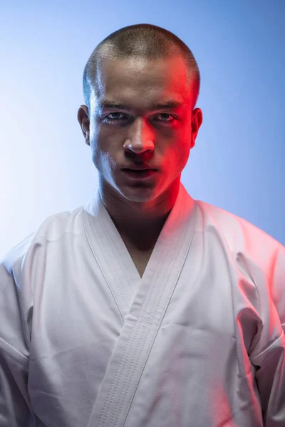 Zugeschnittene Nahaufnahme eines jungen Profisportlers in weißem Kimono, isoliert über weißblauem Hintergrund. Karate, Judo, Taekwondo — Stockfoto