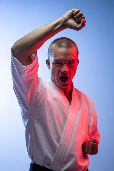 Beskuren bild av ung professionell idrottsman i vit kimono isolerad över vit blå backgroud. Karate, judo, taekwondo sport — Stockfoto