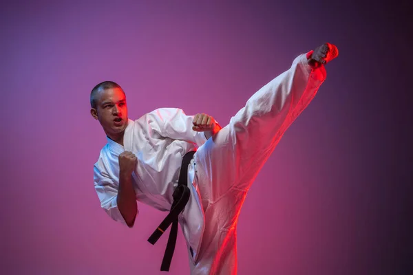 Retrato recortado de un hombre caucásico guapo en kimono entrenamiento arte marcial sobre fondo rosa púrpura degradado. Karate, judo, taekwondo sport — Foto de Stock