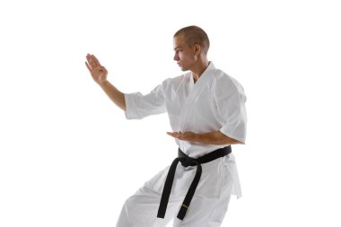 Beyaz arka planda izole edilmiş beyaz tenli bir sporcu eğitiminin kırpılmış görüntüsü. Karate, judo, tekvando sporu