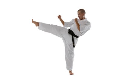 Beyaz arka planda beyaz tenli sporcunun yan tekme atarken çekilmiş portresi. Karate, judo, tekvando sporu