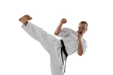 Beyaz arka planda beyaz tenli sporcunun yan tekme atarken çekilmiş portresi. Karate, judo, tekvando sporu