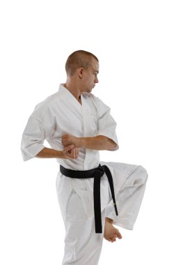 Yan görüş. Kafkasyalı bir sporcu beyaz arka planda yalnız poz veriyor. Karate, judo, tekvando sporu