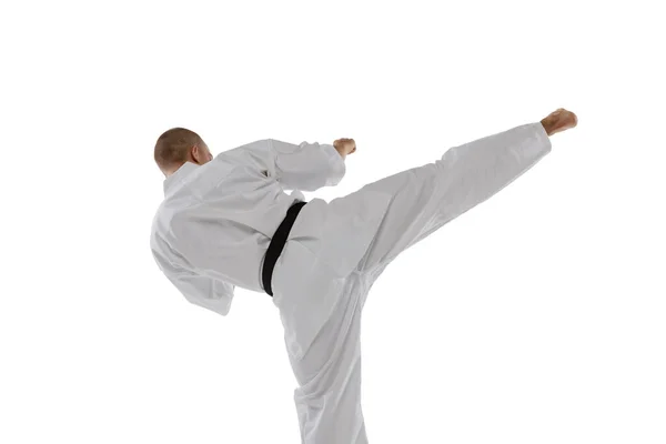 Bakåt. Beskurna porträtt av kaukasisk idrottsman stående i sidan kick pose isolerad över vit bakgrund. Karate, judo, taekwondo sport — Stockfoto