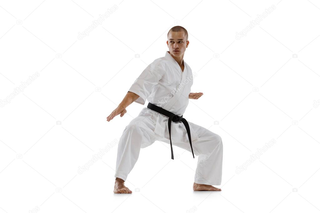 Full-length portrait of caucasian sportsman standing in a fight pose isolated over white background. Karate, judo, taekwondo sport