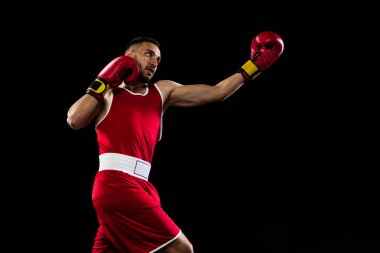 Aparkat yumruklama. Siyah arka planda izole edilmiş kırmızı üniformalı bir boksörün portresi. Dövüşçü iş başında çalışıyor. Sağlık, spor, hareket konsepti. İlan için alanı kopyala.