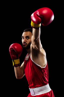 Yumruk atmaya hazırım. Siyah arka planda izole edilmiş kırmızı üniformalı bir boksörün portresi. Dövüşçü iş başında çalışıyor. Sağlık, spor, hareket konsepti. İlan için alanı kopyala.