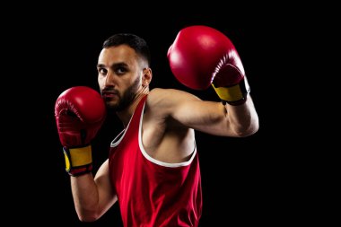 Yumruk atmaya hazırım. Siyah arka planda izole edilmiş kırmızı üniformalı bir boksörün portresi. Dövüşçü iş başında çalışıyor. Sağlık, spor, hareket konsepti. İlan için alanı kopyala.