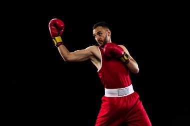 Aparkat pozisyonu. Siyah arka planda izole edilmiş kırmızı üniformalı bir boksörün portresi. Dövüşçü iş başında çalışıyor. Sağlık, spor, hareket konsepti. İlan için alanı kopyala.