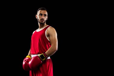 Siyah arka planda izole edilmiş kırmızı üniformalı genç profesyonel boksörün kırpılmış görüntüsü. Sportif ve sağlıklı yaşam tarzını sürdürüyor. Sağlık, spor, hareket konsepti. İlan için alanı kopyala.