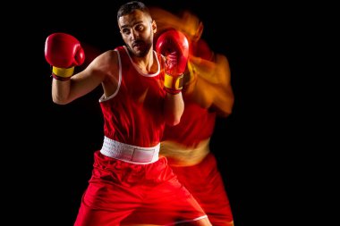 Bir profesyonel erkek boksör eğitimi karışık ışıkta siyah arka plan üzerinde izole edilmiş. Sert yumruk hareketi. Karışık ışık effeti