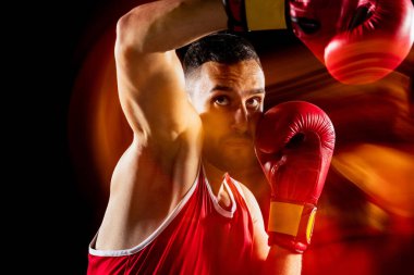 Siyah arka planda izole edilmiş profesyonel bir erkek boksör eğitiminin karışık ışık altında görüntüsü. Karşıt saldırı. Yumruk