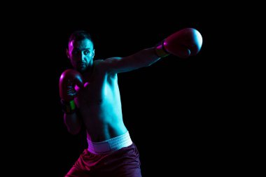 Bir profesyonel erkek boksör eğitimi neon ışıkta siyah arka plan üzerinde izole edilmiş. Rakibi nakavt etmek