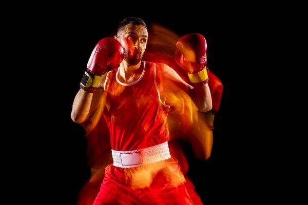 Egy profi férfi bokszoló edzés elszigetelt fekete háttér vegyes fényben. Ellenséges támadás. Ütés — Stock Fotó