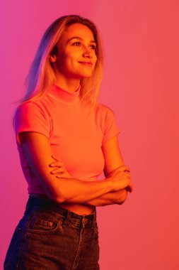 Neon ışıklarıyla izole edilmiş, gülümseyen ve poz veren genç bir kızın dikey görüntüsü.