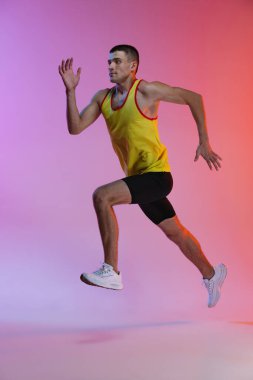 Gradyan stüdyo arka planında izole bir şekilde koşan genç bir erkek sporcunun portresi. Dayanıklılık geliştiriliyor